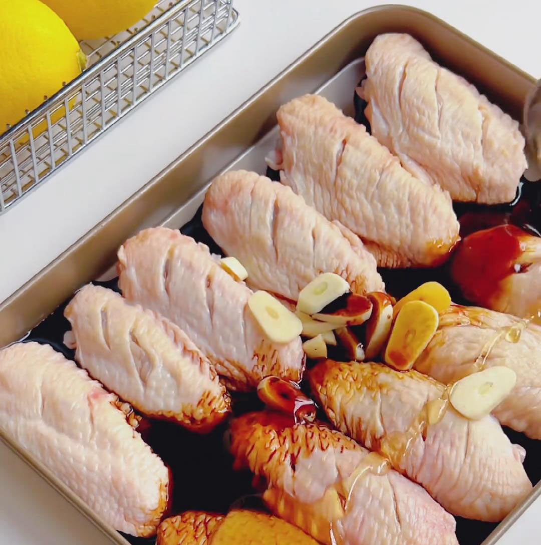 Place the wings in a large bowl and add the garlic slices, light soy sauce, dark soy sauce, oyster sauce, honey, black pepper, and salt.