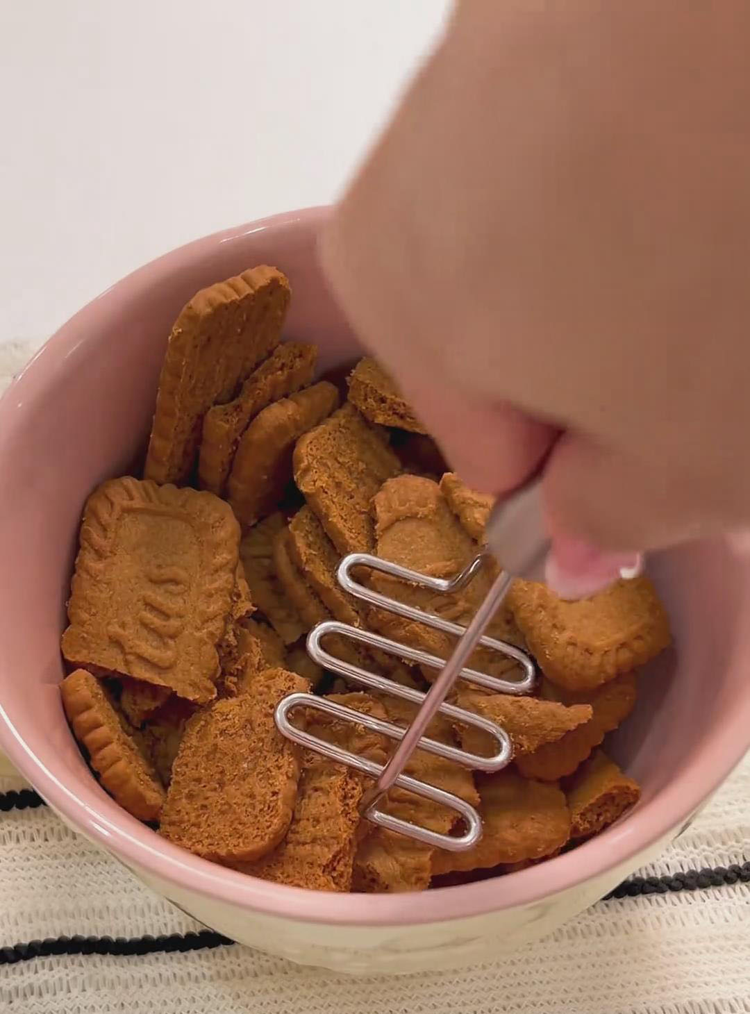 Add the Biscoff cookies to a large bowl and crush them using a smasher