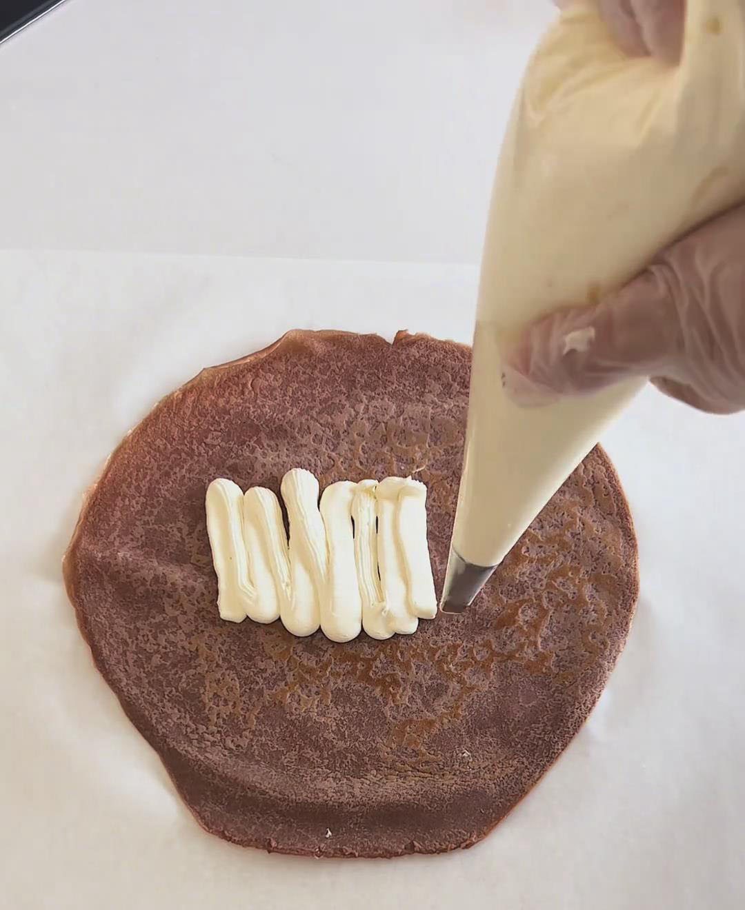 Pipe an even layer of whipped cream over the crepe