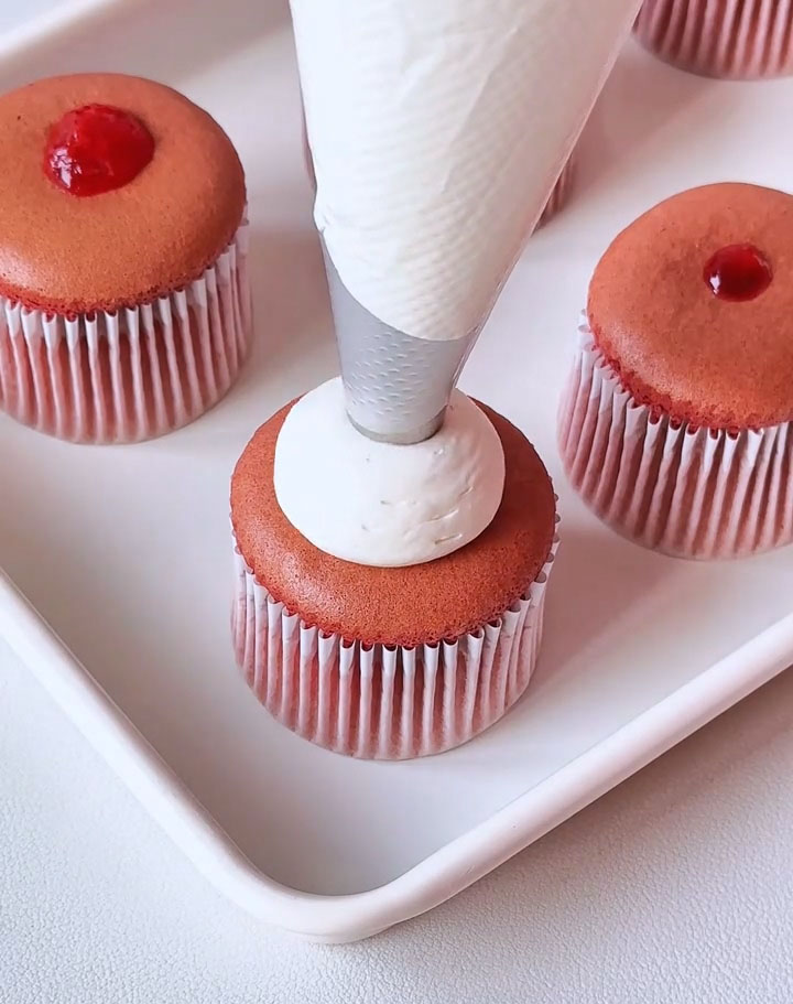 Pipe a generous swirl of the whipped cream on top of each cupcake