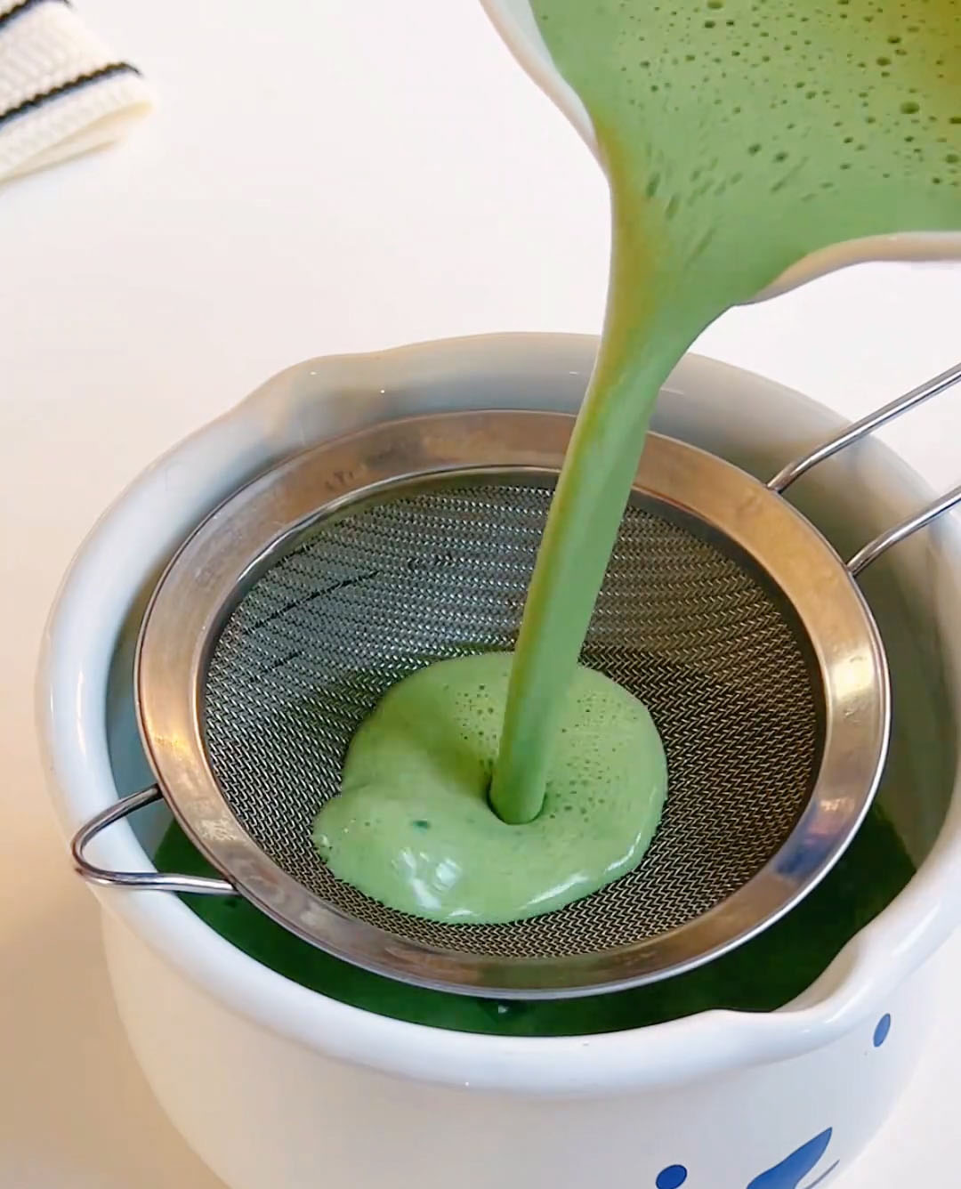 Pour the matcha milk mixture through the sieve into the pan