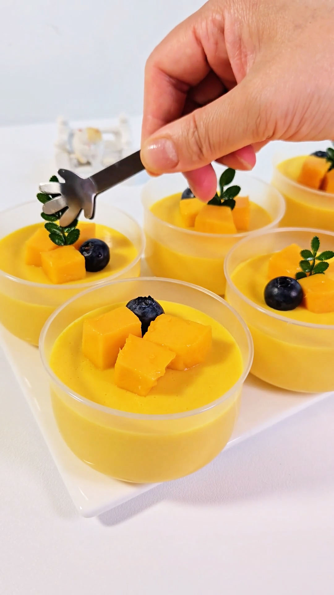 Garnish the top of each pudding with fresh mango cubes, a few blueberries, and a small sprig of mint leaves for a vibrant