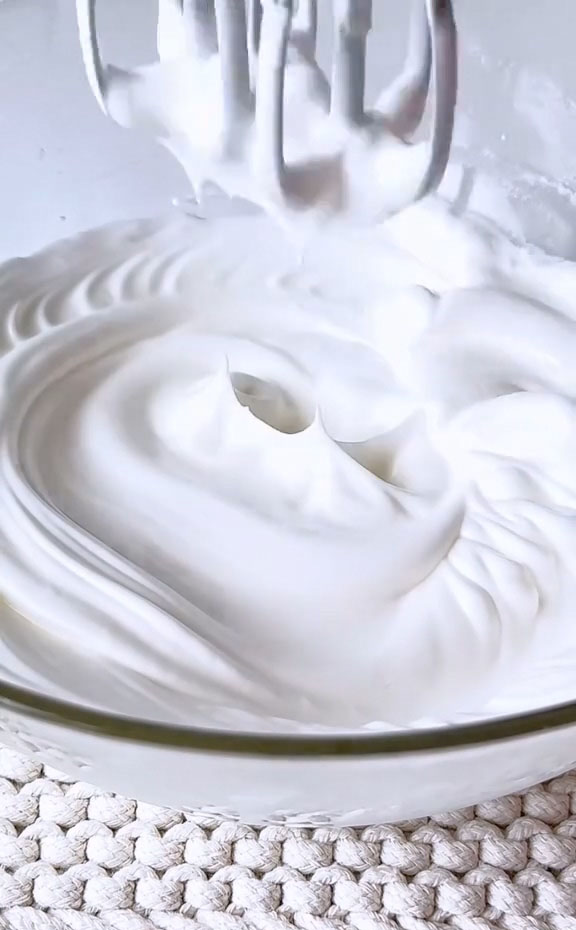 In a clean bowl, whip the egg whites with sugar until stiff peaks form