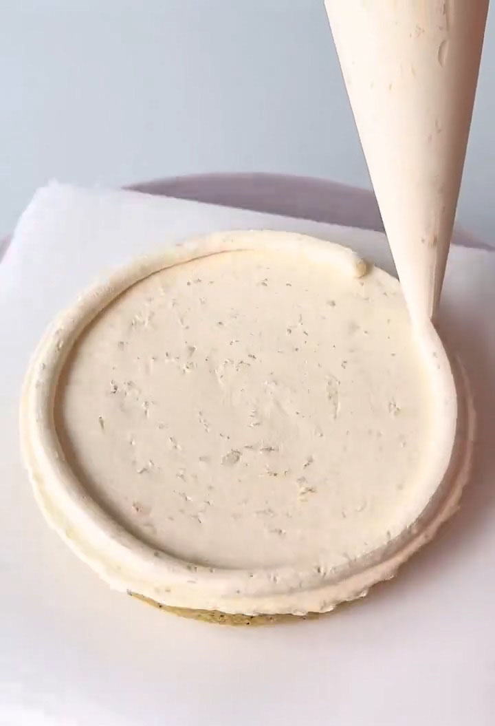 Pipe two rings of cream around the perimeter of the cake layer to create a dam that will hold the jam in place