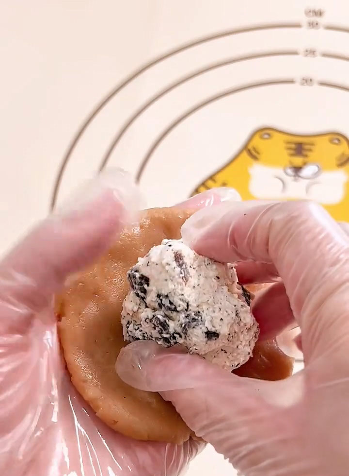 Place one 30 g ball of milk tea cream cheese filling in the center of the disc