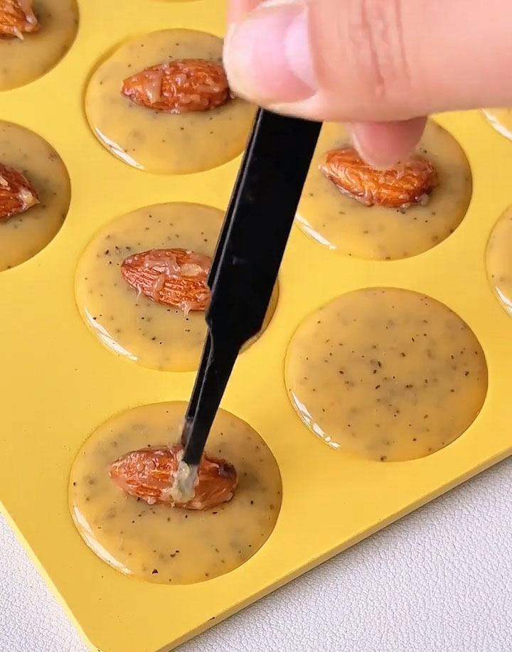 Place one glazed almond onto the center of each piped batter circle