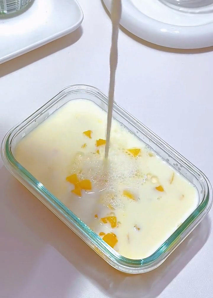 pour the mixture over the mango cubes in the container