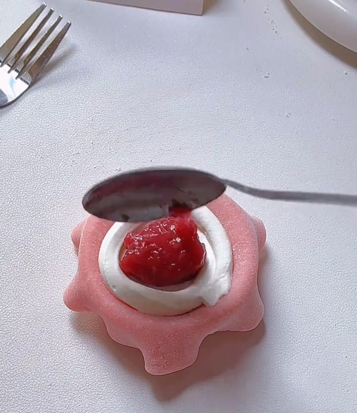 Add one small spoonful of strawberry jam directly onto the center of the cream