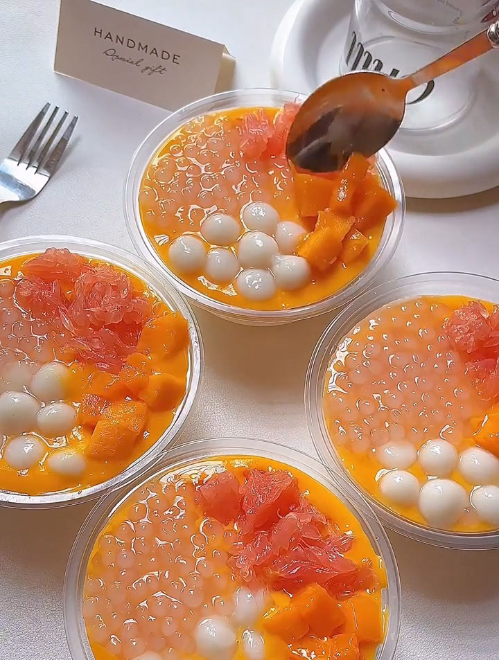 Arrange the cooked tapioca pearls (sago), glutinous rice balls (if using), pomelo segments, and fresh mango chunks over the mango puree.