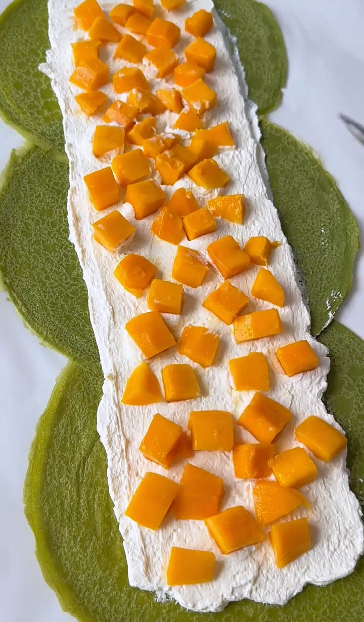 Arrange the fresh mango cubes in a line down the center of the crepes