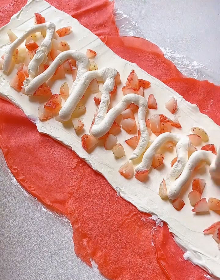 Pipe or spread a second, thinner layer of cream over the strawberries